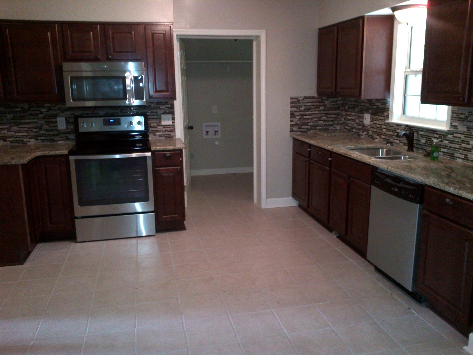Finished kitchen with dark cabinetry and tile backsplash